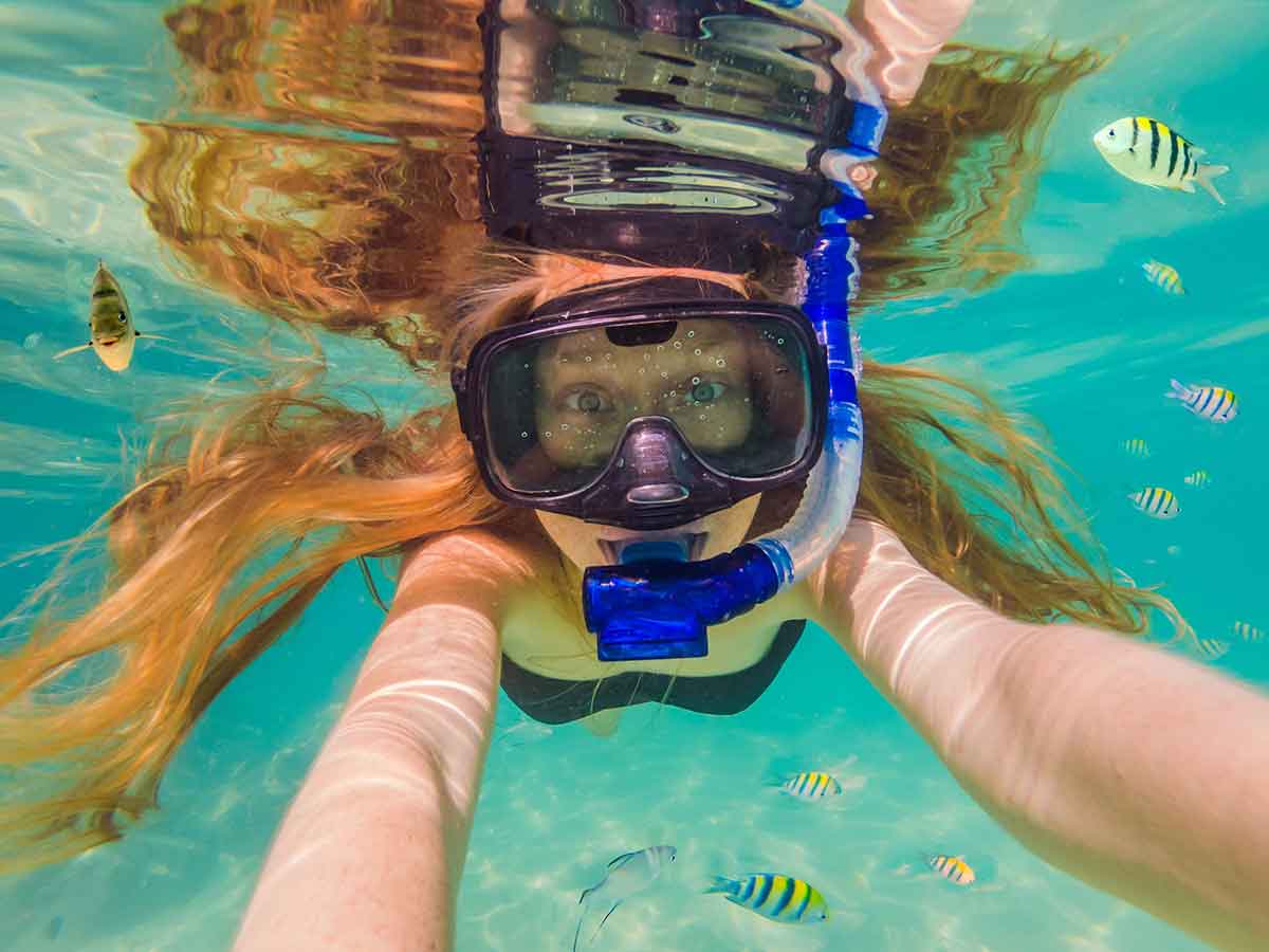 Happy young woman swimming underwater in the tropical ocean.