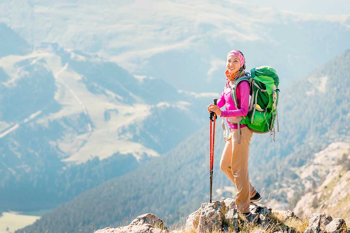 Young woman backpacker tourist standing on a top of the mountain ridge.