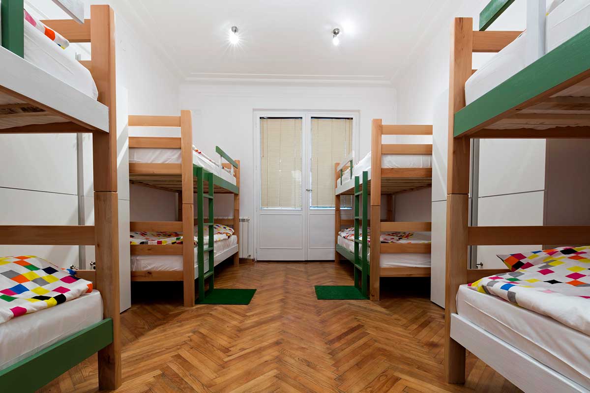 Four bunk beds with colorful bedding in a hostel room.