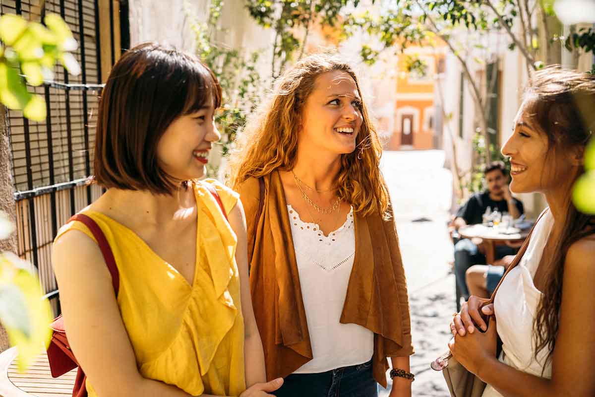 Three women walking down the street and talking on a sunny day