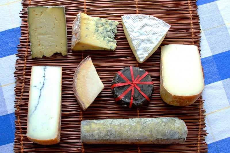 wicker cheese board with assorted cheeses in a line