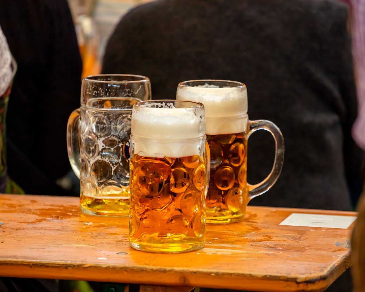 Mugs of Bavarian beer on a wooden desk, closeup view. Oktoberfest, Munich, Germany.