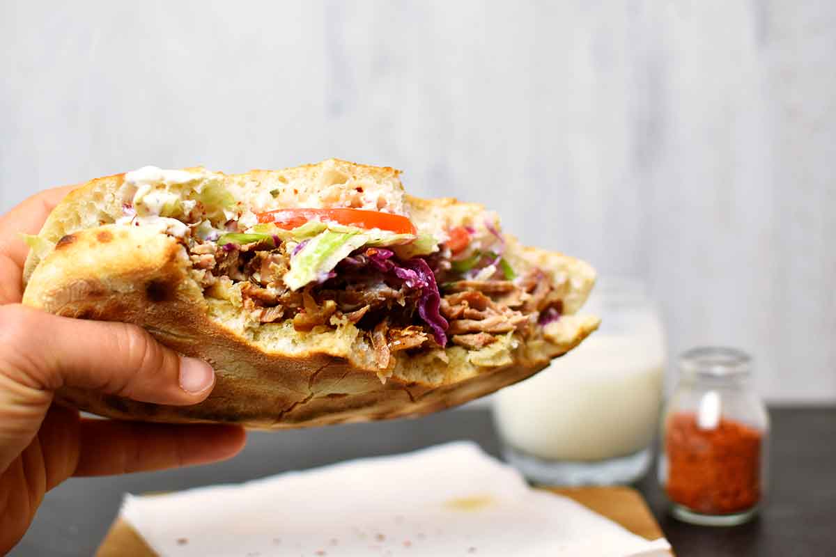 Delicious, fresh kebab from Germany on a wooden surface, next to ayran and hot spices