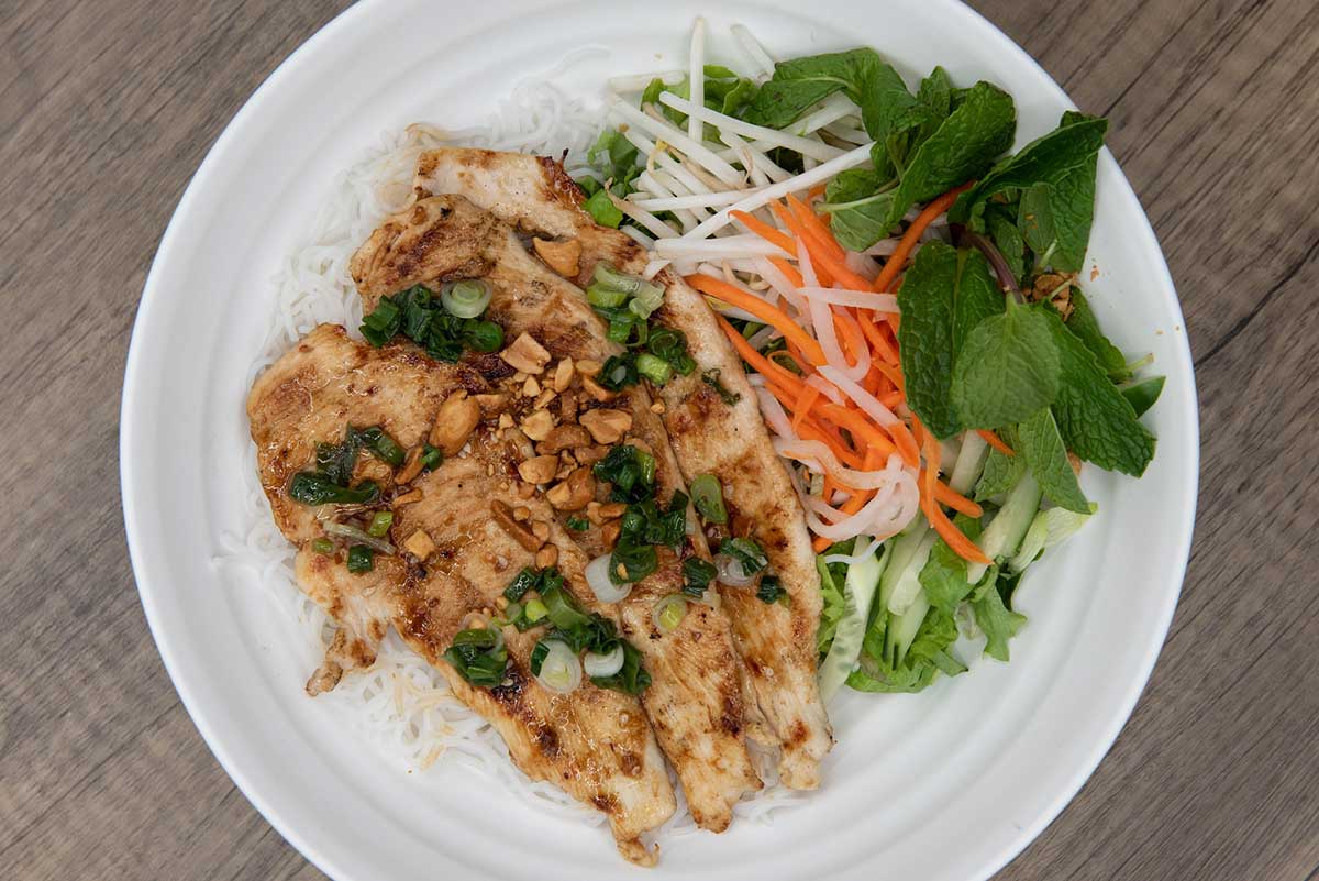 Overhead view of delicious grilled chicken for a Vietnamese meal served with vermicelli in a bowl.
