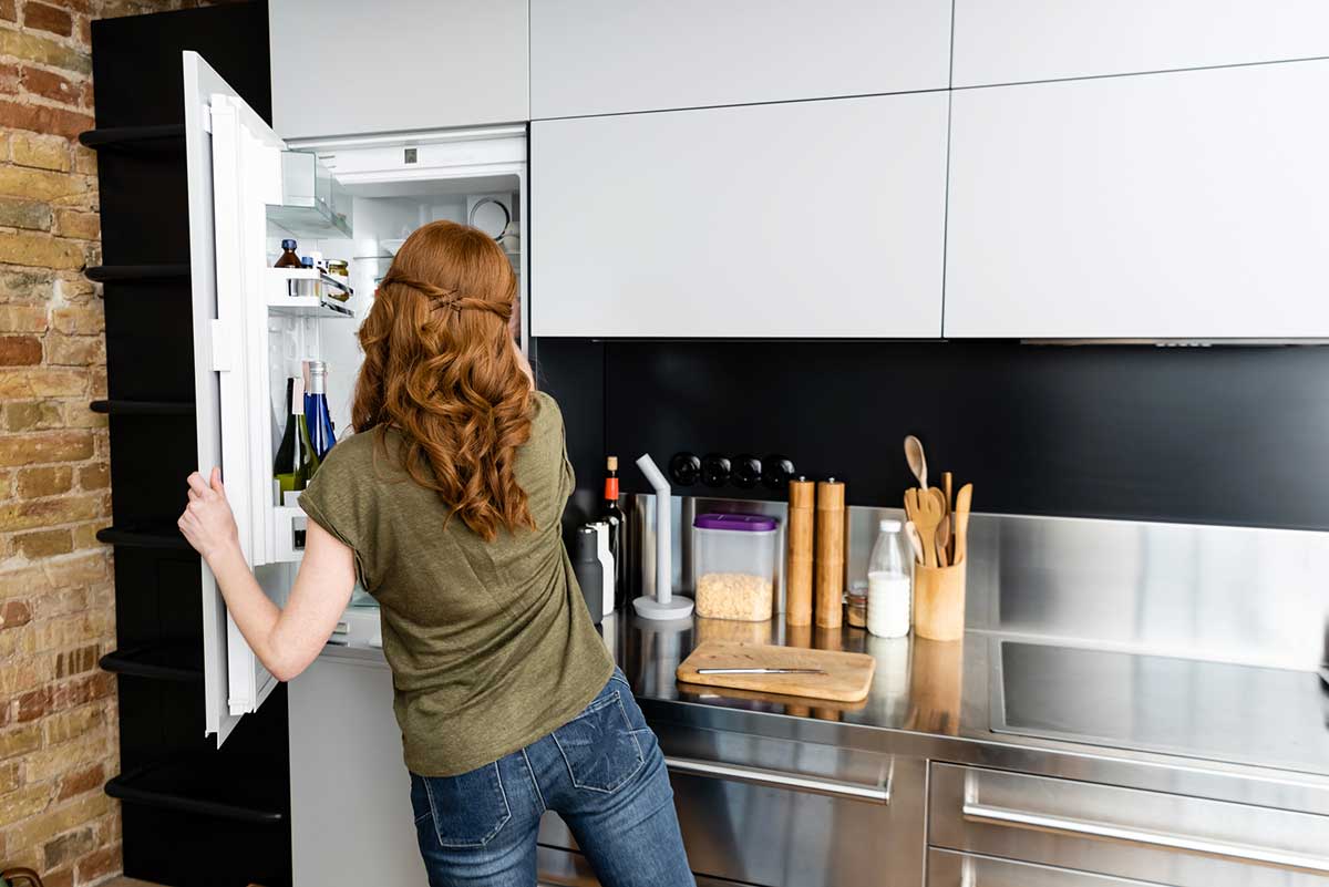 Woman clearing out the fridge in the kitchen before her vacation.