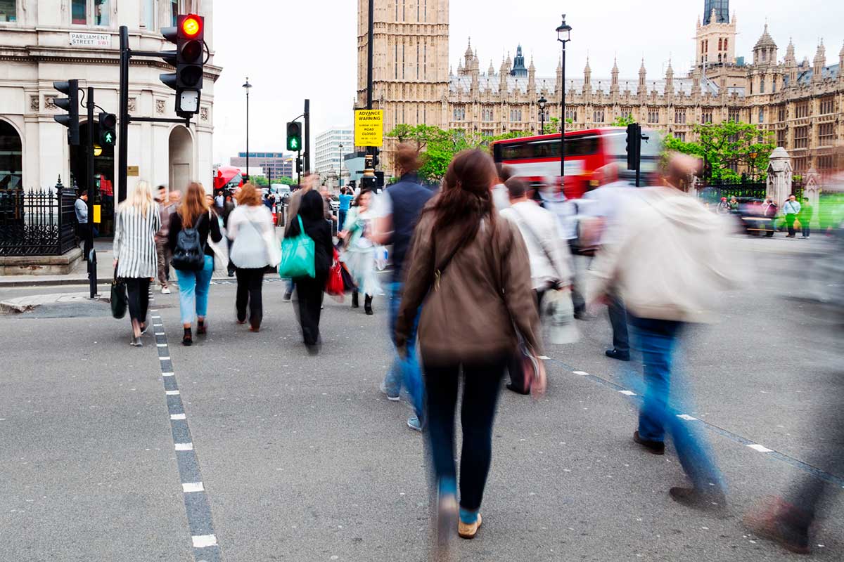 People in motion blur crossing a street near Westminster Palace in London, UK.