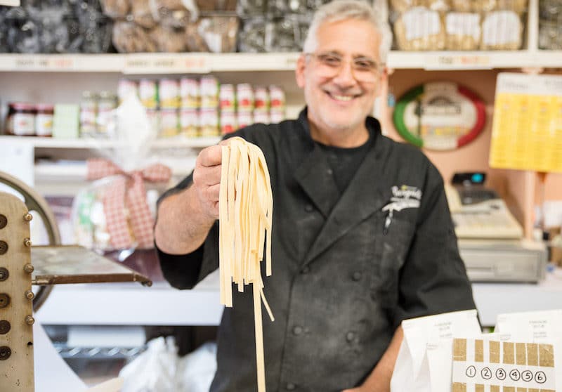 man holding up handmade pasta at Borgatti's in The Bronx