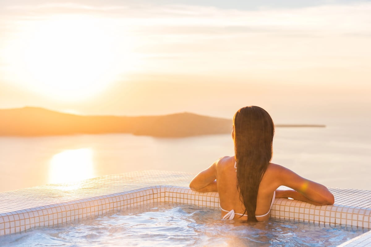 woman gazing out at a sunset view from her Caribbean wellness resort hot tub