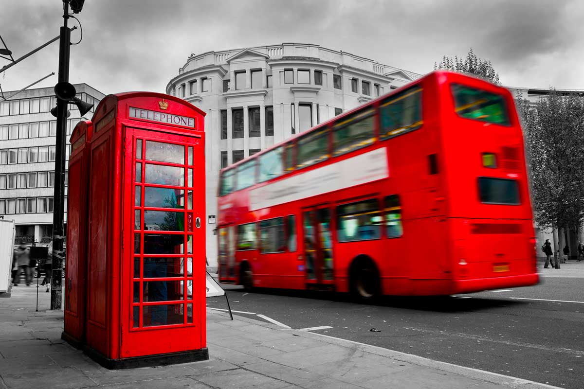 London, the UK. Red phone booth and red bus in motion.