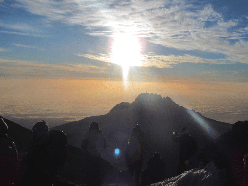sun shining through clouds while climbing kilimanjaro 