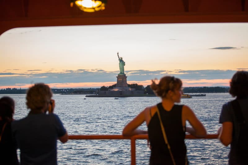 Woman taking in a view of the Stateuf of Liberty from the Staten Island Ferry on a solo trip to NYC
