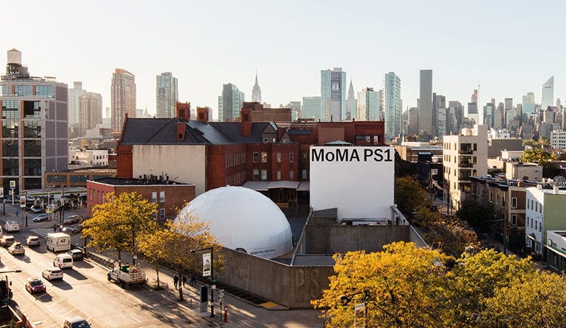 Seeing MoMA PS1 in Queens with the Manhattan skyline behind it on a solo trip to NYC