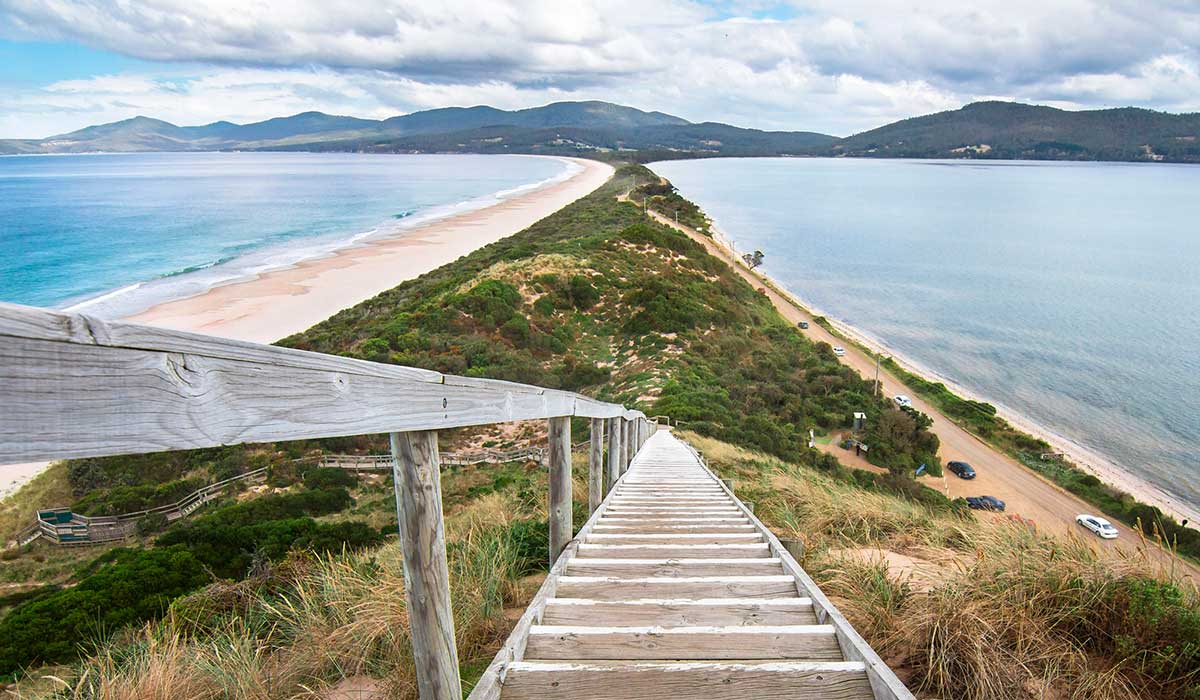 Looking down a staircase at a very narrow isthmus with a road along it on Bruny Island, Tasmania