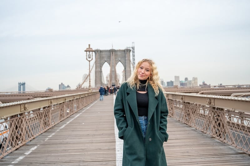 Woman walking the Brooklyn Bridge on a solo trip to NYC