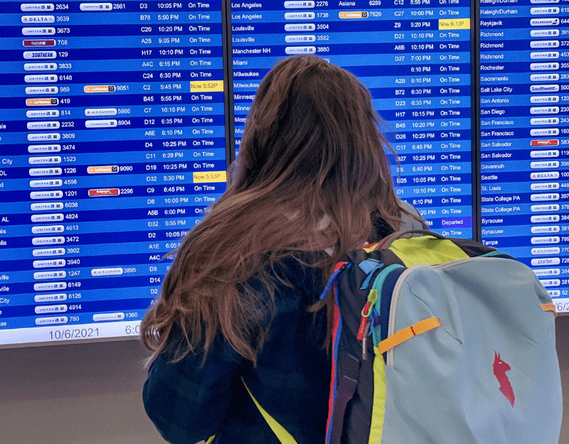 woman looking at airport flight board as she sets off to become a digital nomad 