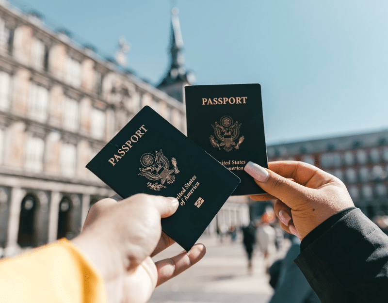 Two digital nomads holding up their passports