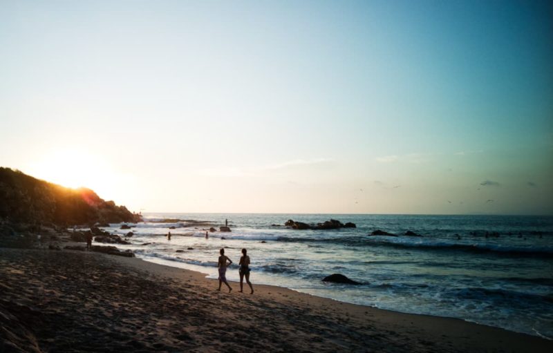 travelers wandering the beach in Puerto Escondido, one of the best places in Mexico to travel alone
