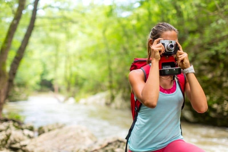 woman hiking solo and taking photos with a camera