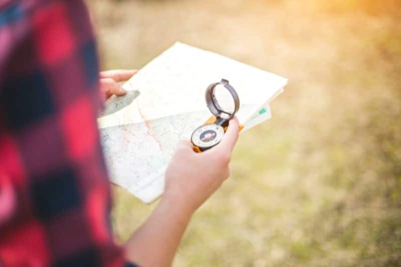 solo female hiker holding a paper hiking map and compass