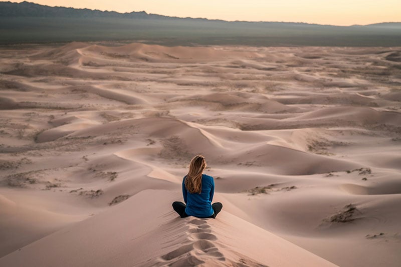 Woman sat in the middle of the desert.