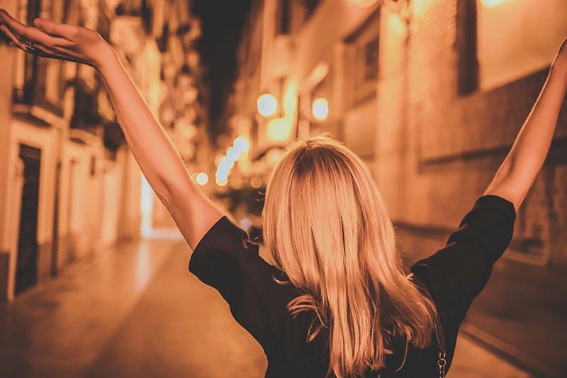 A woman feeling empowered walking down a street at night.