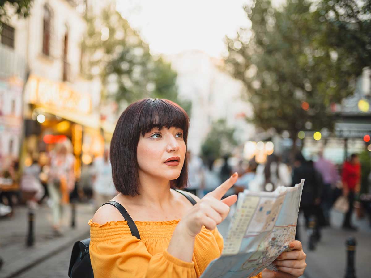 A close up photo of a woman trying to figure out directions while traveling solo.