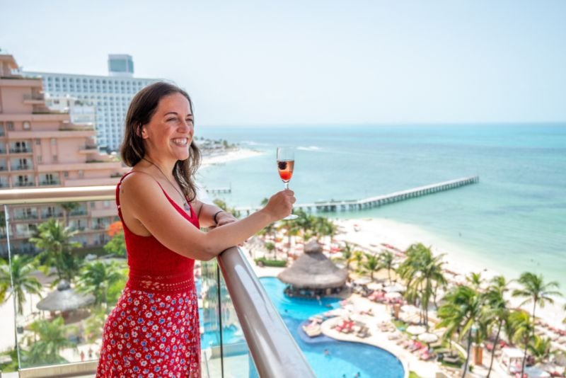 travel blogger holding a glass of wine on a balcony
