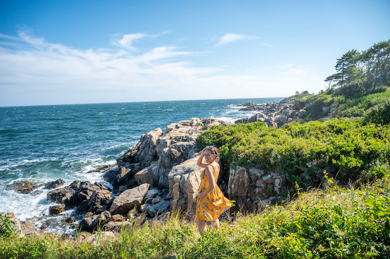 woman looking out over Maine coast on a road trip