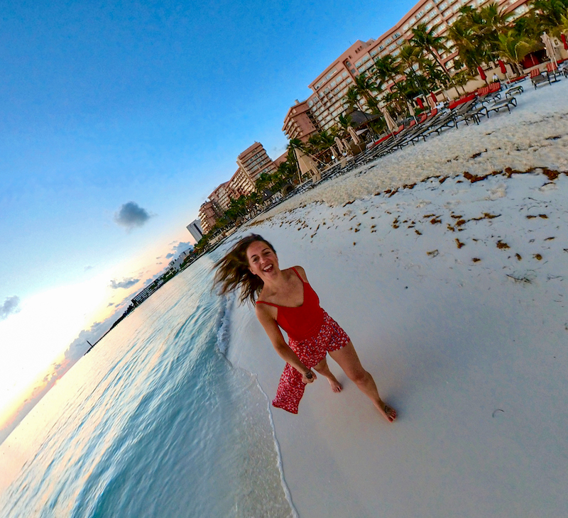 female travel blogger running on beach in Cancun, Mexico