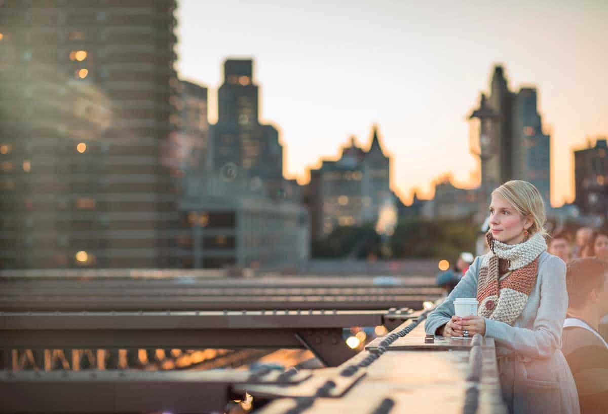 A woman admiring the nyc skyline from brooklyn bridge in nyc.
