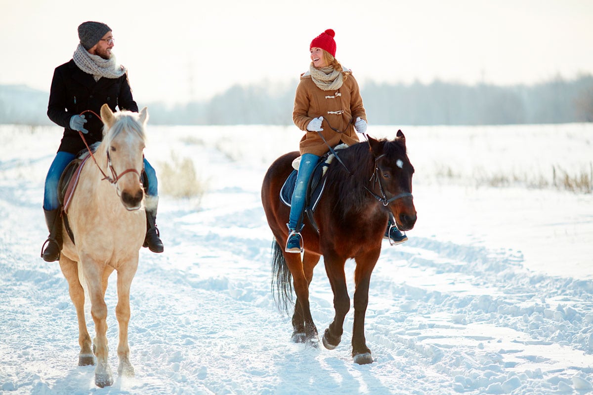 A couple horseback riding in the Catskills in winter.