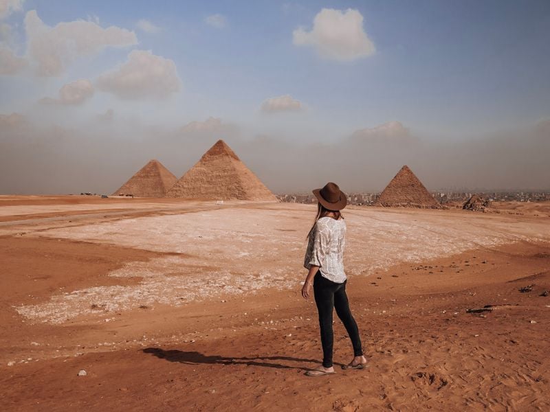 woman gazing out at the Egyptian pyramids while traveling solo through the Middle East