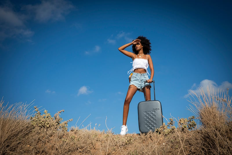 solo female traveler rolling a collapsible suitcase