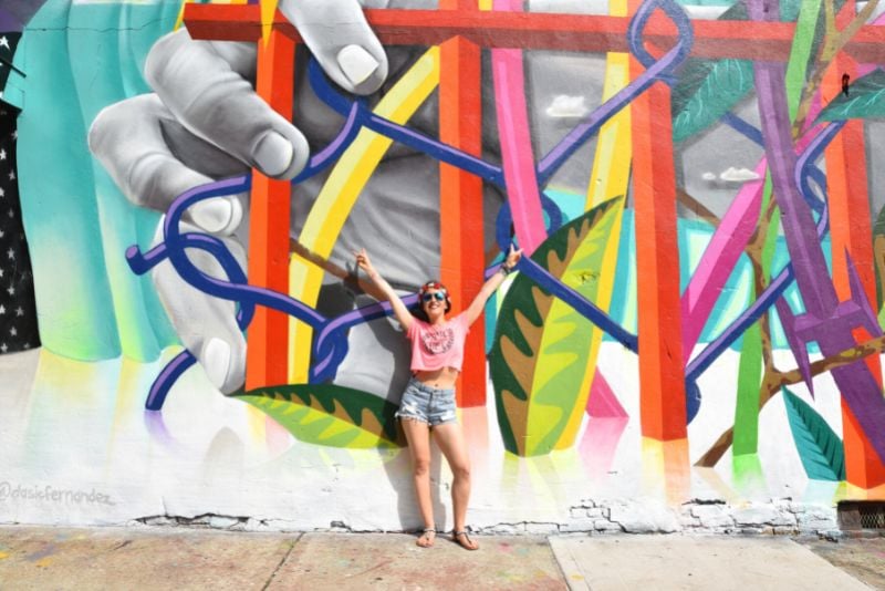 woman posing in front of a mural within the Bushwick Collective in Brooklyn