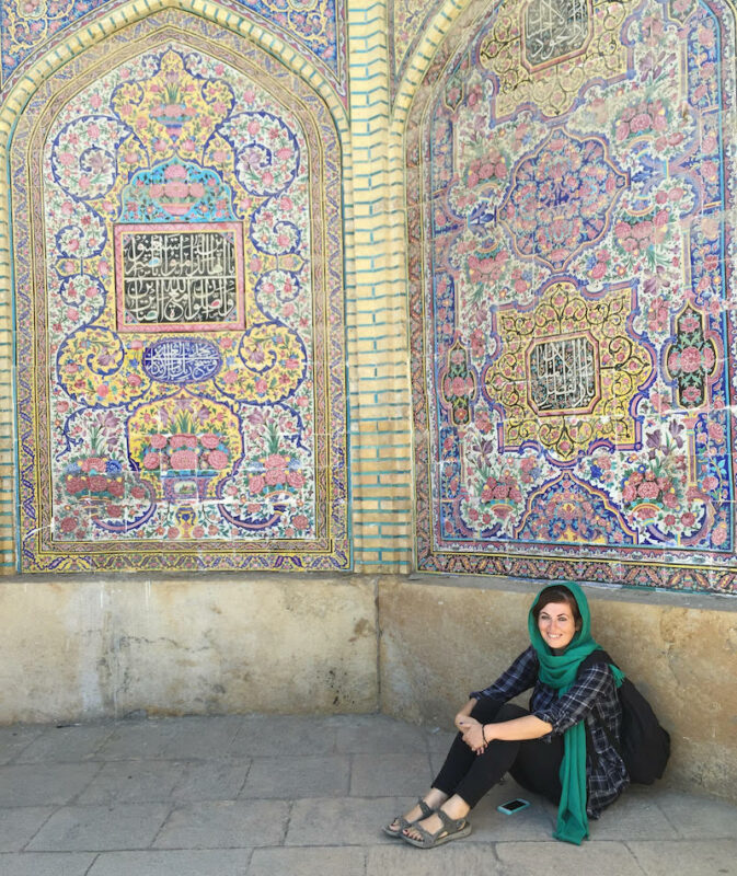 solo female traveler in the Middle East sitting in front of mosaic tilework in Iran