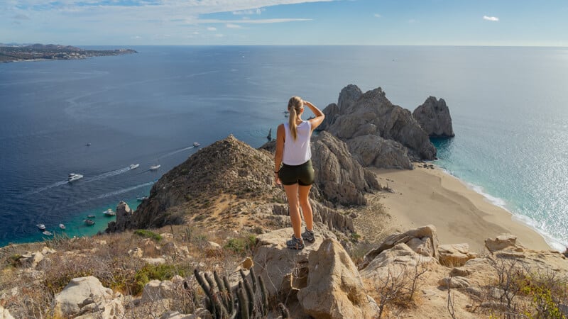 woman gazing out over Lands End from the top of Mt Solmar after hiking Baja California
