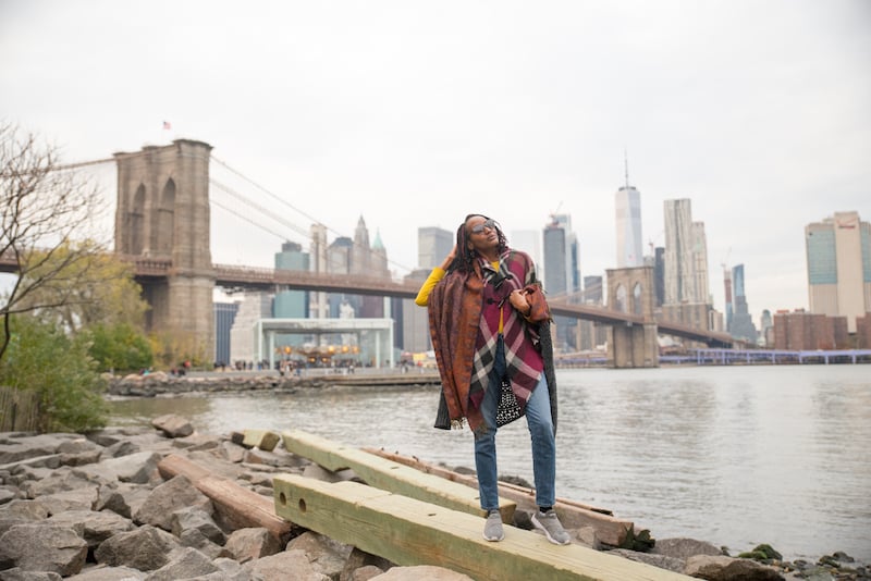 woman posing in front of the Manhattan skyline in DUMBO on a New York City architectural tour