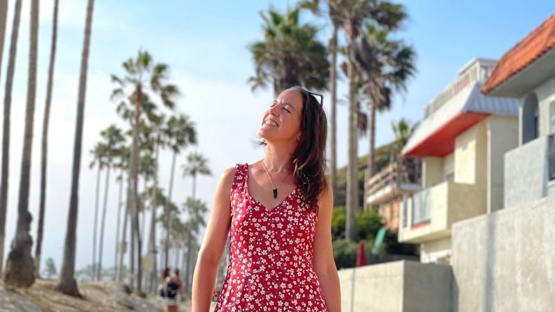 woman on a solo trip to Los Angeles walking underneath palm trees