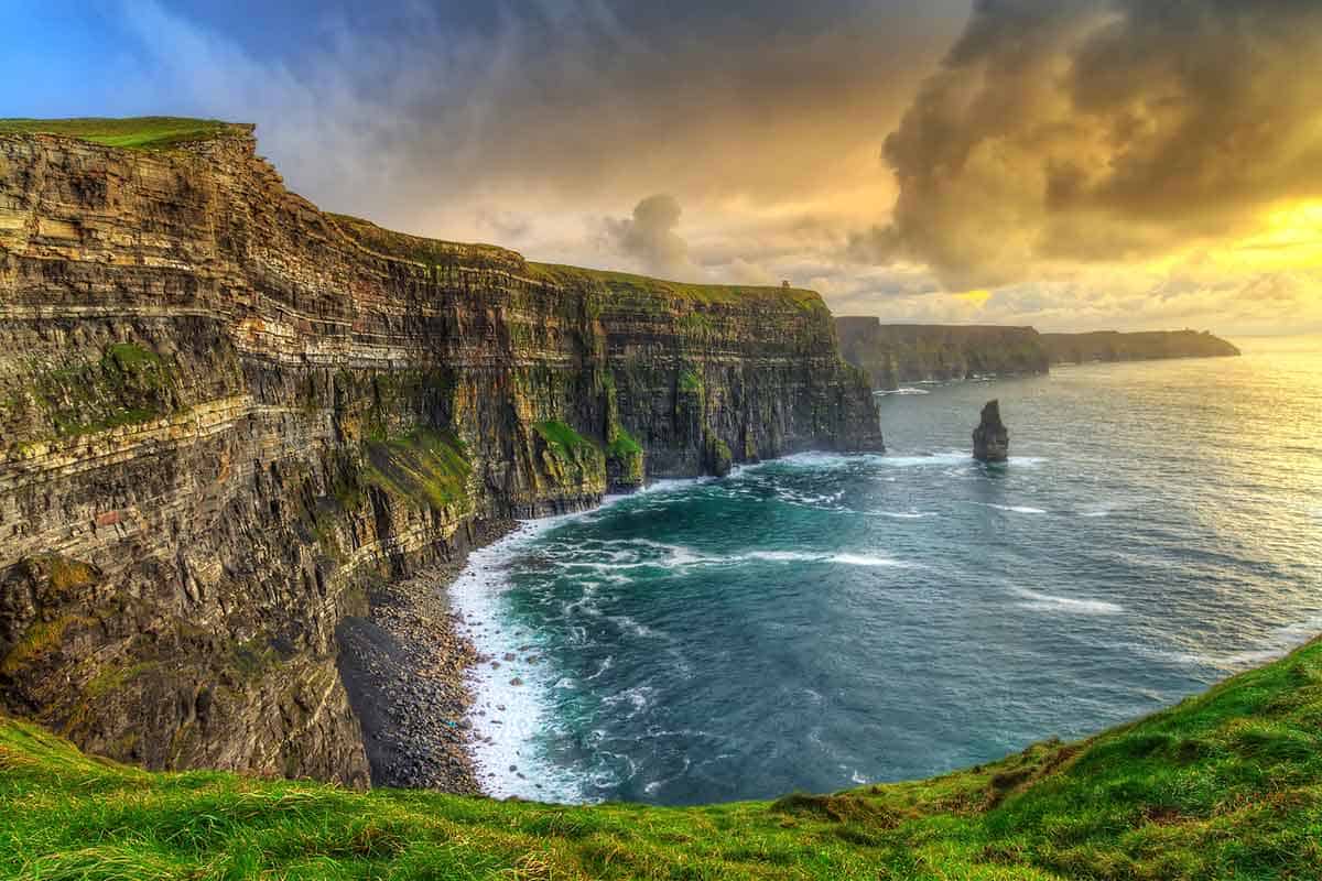 woman visiting the giant Cliffs of Moher at sunset while traveling Ireland solo