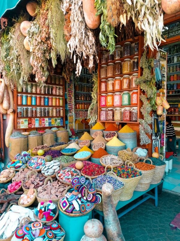 solo female traveler in Morocco perusing colorful bags of spices in Marrakech