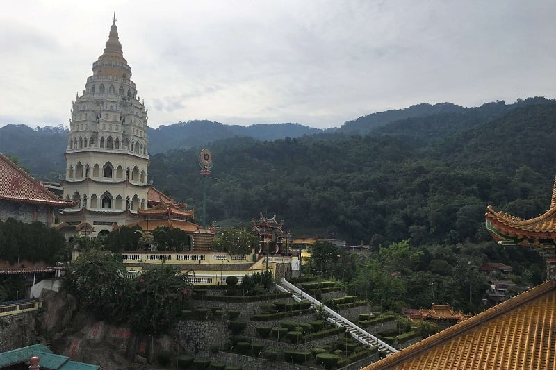 Solo traveler in Malaysia visiting the Kek Lok Si Temple surrounded by lush green hills dotted with trees
