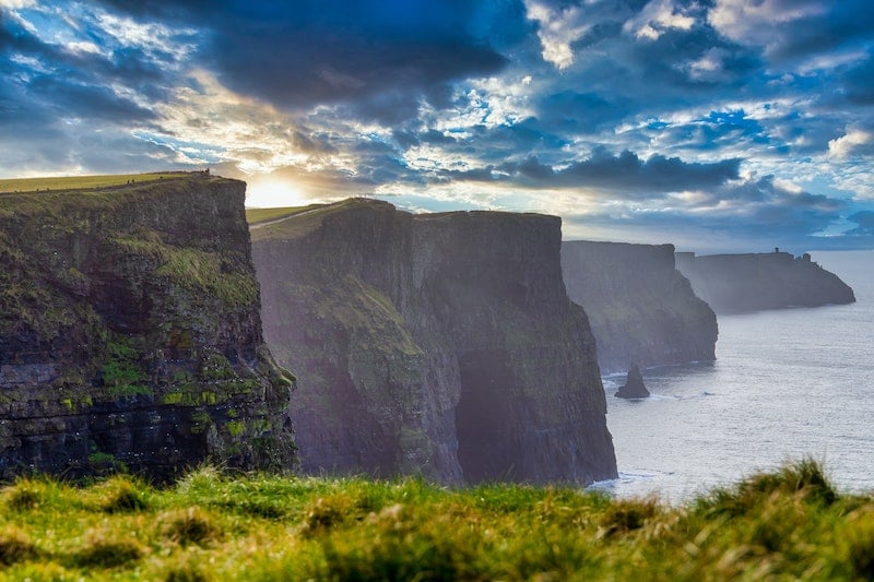 woman visiting the giant Cliffs of Moher while traveling Ireland solo