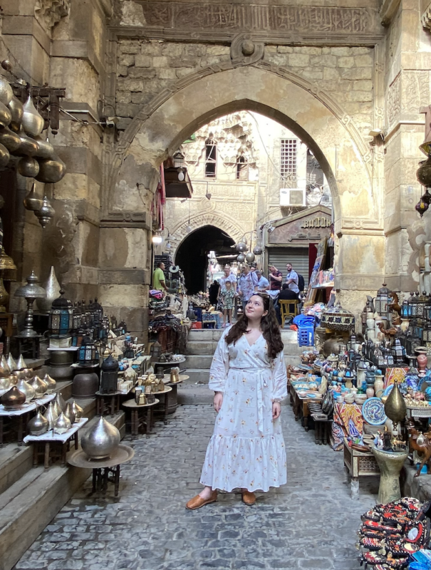 solo female traveler in Morocco posing for a photo next to souk shopping stalls
