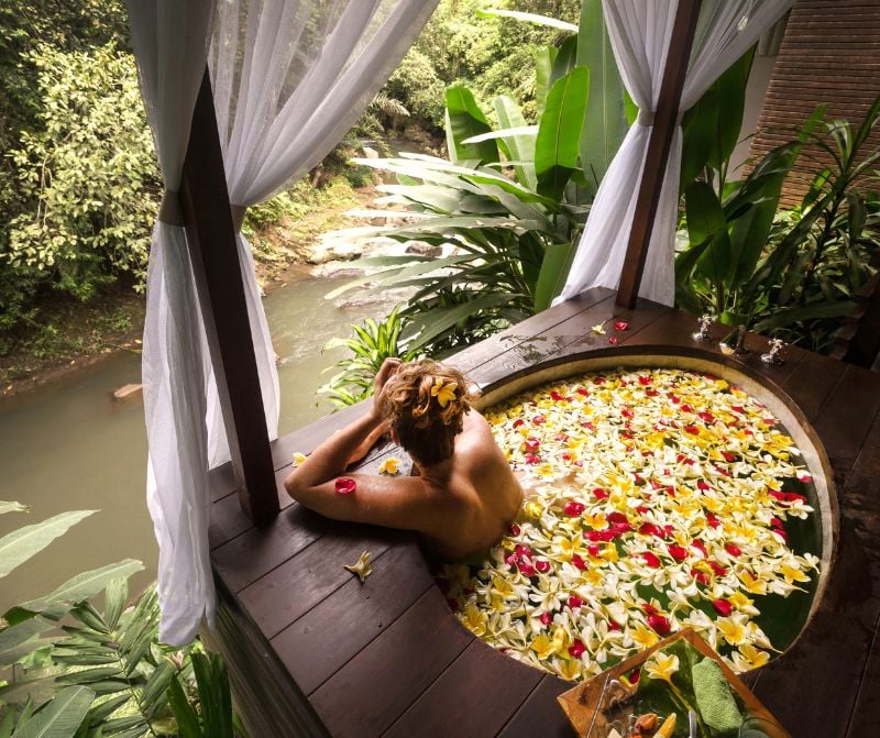 woman in a Balinese flower bath overlooking a river