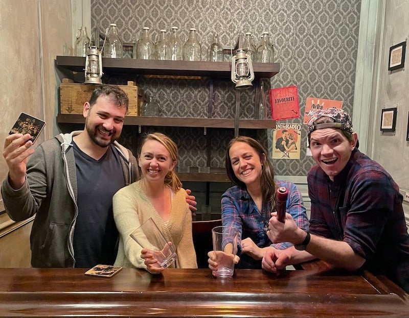 group of friends holding glasses to cheers in Clue Chase's Moonshine Madness Escape Room on a rainy day in NYC