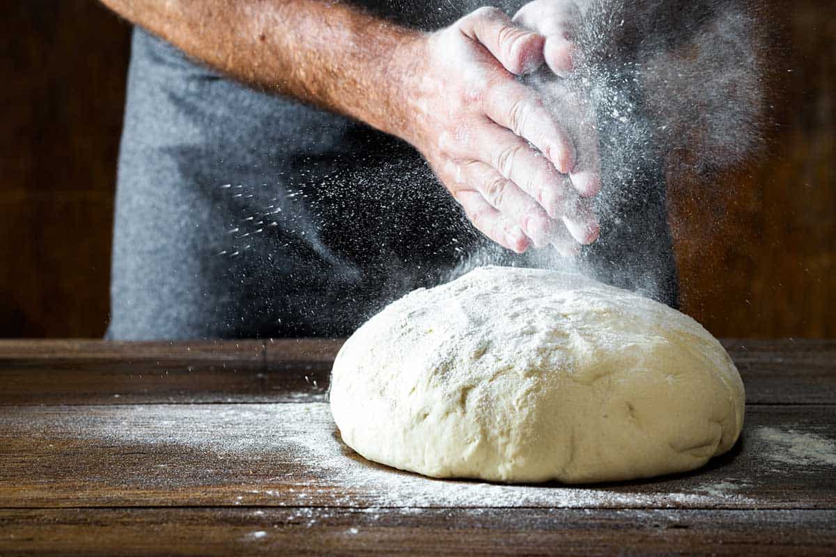 Preparing pizza dough on a wodden table in bakery