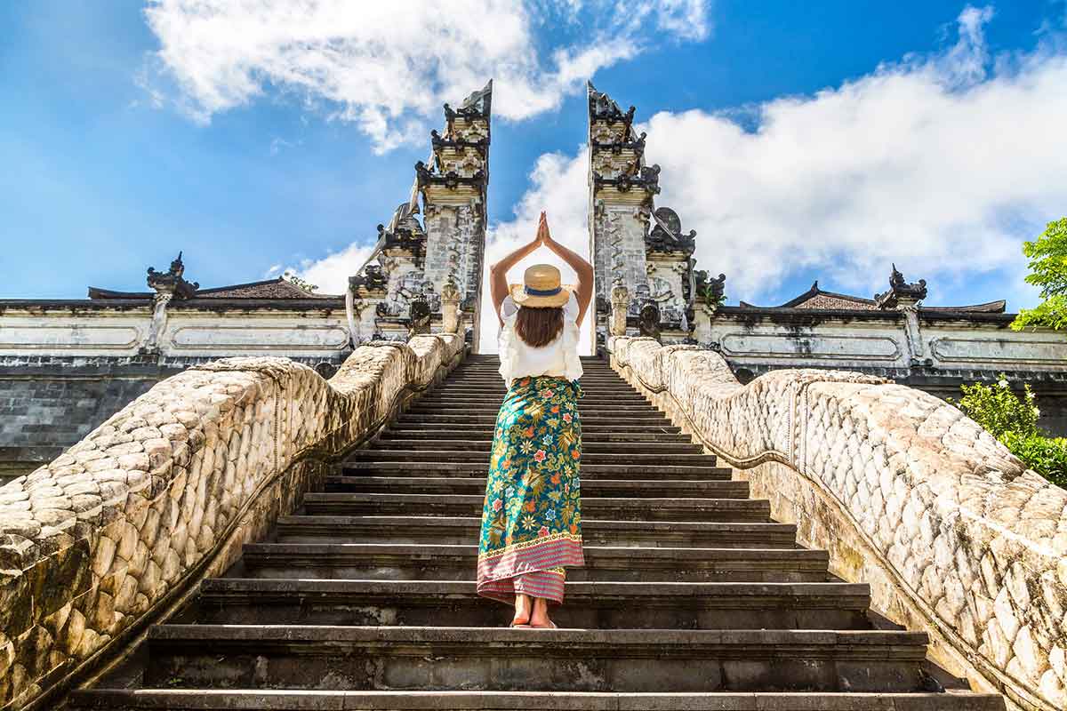Woman traveler at Ancient gate at Pura Penataran Agung Lempuyang temple on Bali, Indonesia.