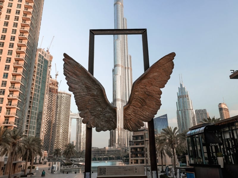 woman viewing a butterfly sculpture in front of the Burj Khalifa on a solo trip to Dubai