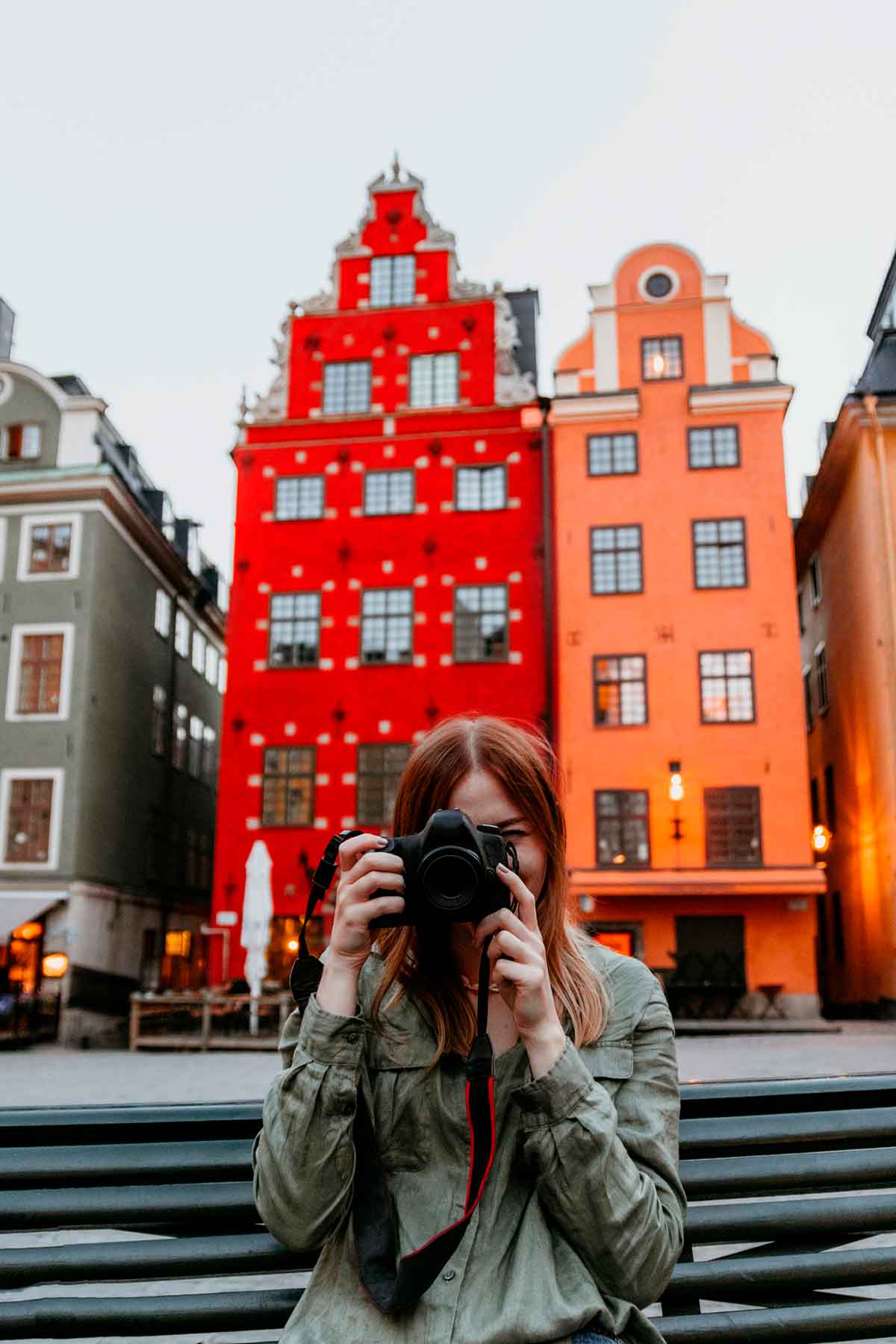 Woman taking photos with her camera of traditional buildings in Stockholm, Sweden.