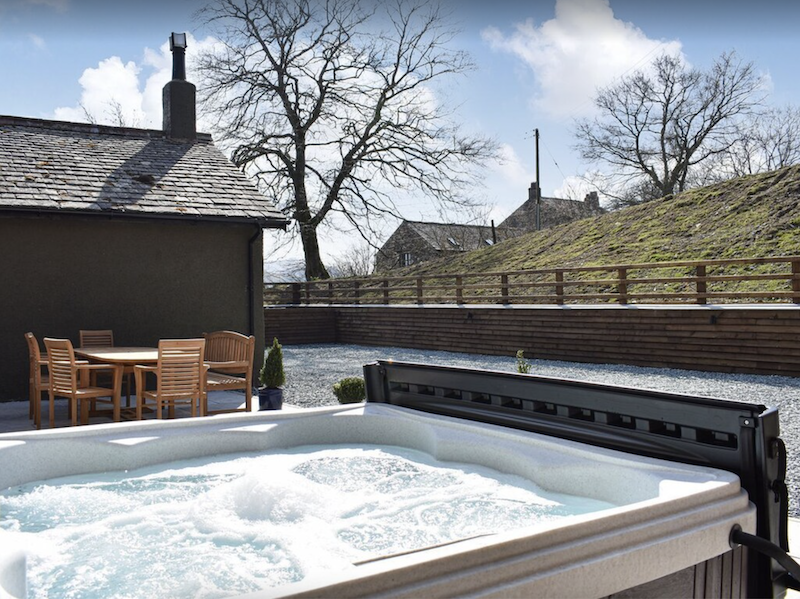 lodge with wooden picnic table next an outdoor hot tub in the Lake District